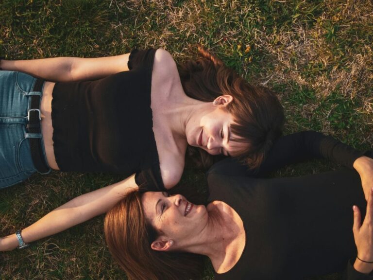 older woman and younger woman lying side by side in the grass