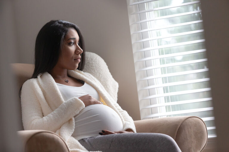 Pregnant woman sitting in chair looking gout of a window